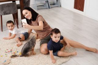 Un enfant assis à distance tend la main vers un chien couché sur son tapis